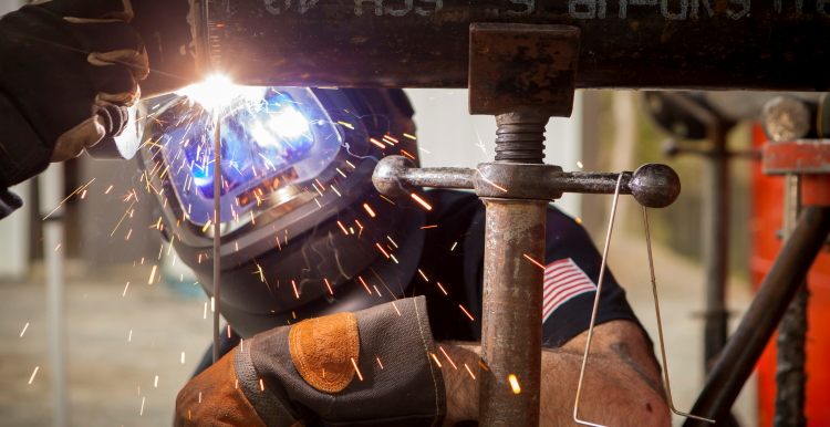 Welder joining steel pipe as sparks fly